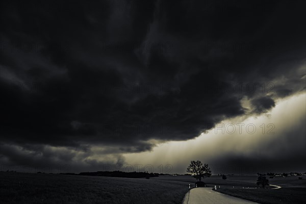 Road and meadows with thunderstorm sky in the background