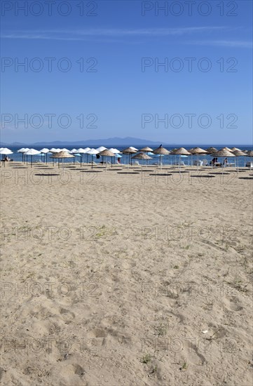 Straw parasols on the sandy beach on the Aegean Sea