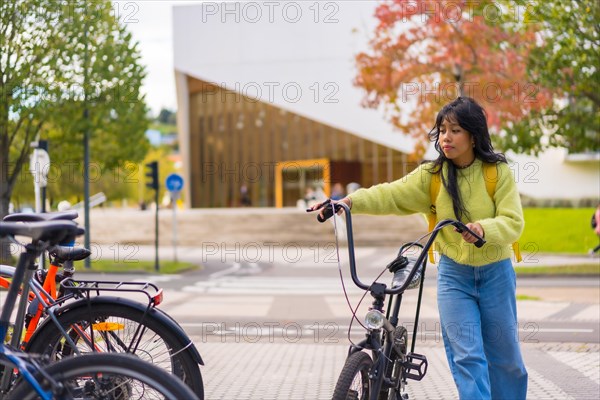 Young asian female student parking the bike in university campus