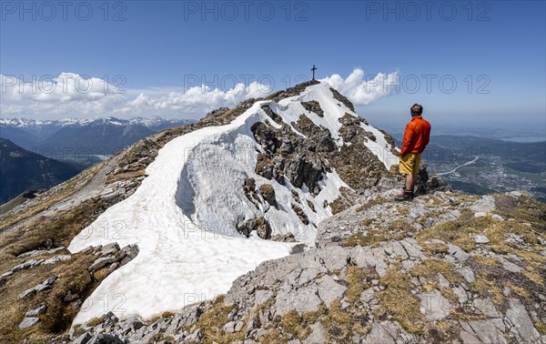 Hiker on the summit ridge of Thaneller with summit cross