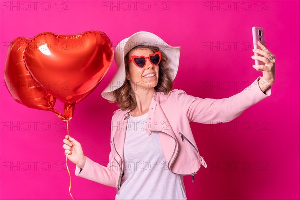 Portrait of a caucasian woman having fun with a white hat in a nightclub with some heart balloons