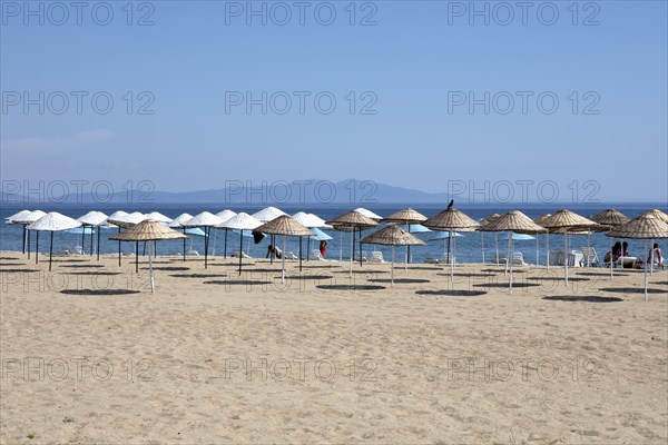 Straw parasols on the sandy beach on the Aegean Sea