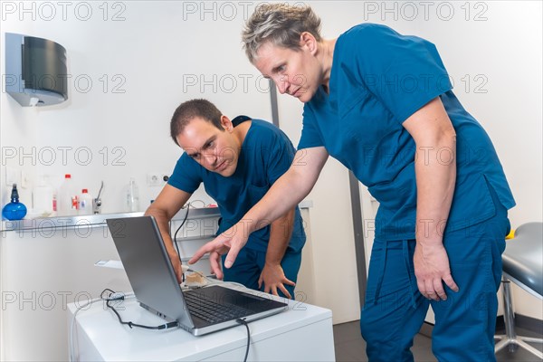 A doctor in the dental clinic explaining to a female doctor how to scan a denture with a computer