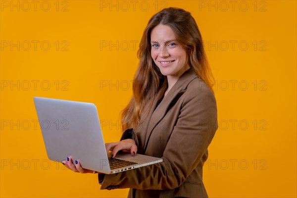 Blue-eyed business woman on a yellow background with a computer