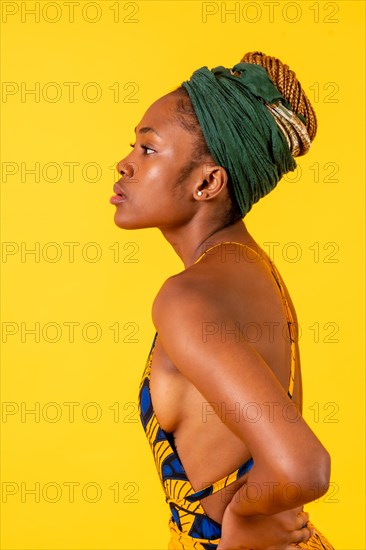 One female person of black ethnicity in traditional costume on yellow background