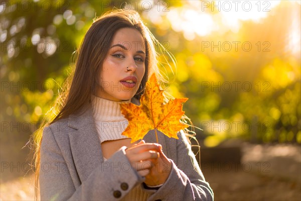 A pretty woman enjoying autumn in a park at sunset