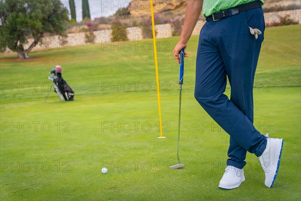 Businessman playing golf and answering a work call with the phone from the club