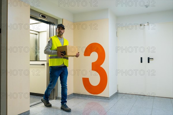 Young delivery man in protective uniform at online order delivery
