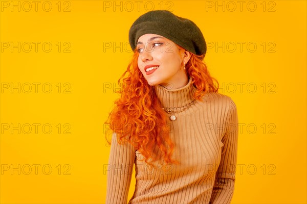 Red-haired woman in beret in studio on a yellow background