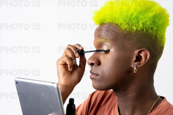 A gay black man putting on makeup