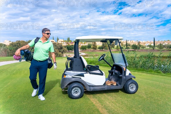 Man in the Buggy with the bag of clubs looking at the course