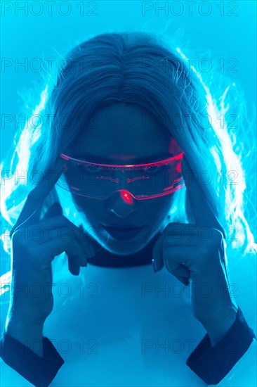 Portrait of a woman in a futuristic suit and glasses with blue led lights