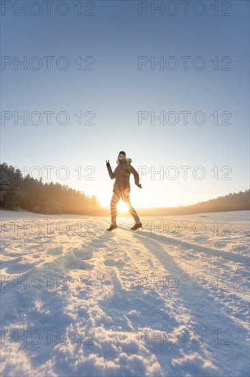 Dancing woman in the snow at sunset