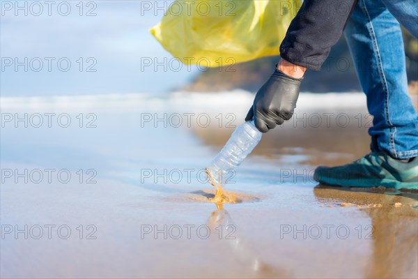 Unrecognizable person collecting garbage or plastic on the beach. ecology concept