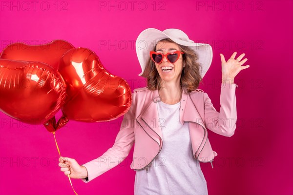 Portrait of a caucasian woman having fun dancing with a white hat in a nightclub with some heart balloons