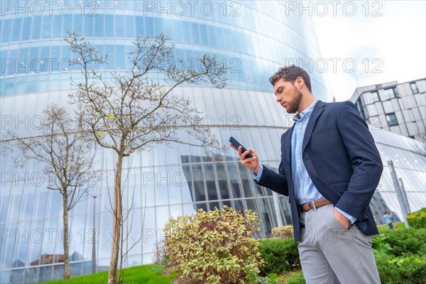 Male businessman or entrepreneur looking at mobile outside the office