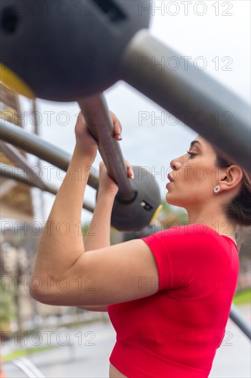Fit woman in red outfit doing arm exercises on some bars