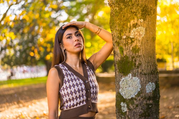 Brunette model in autumn at sunset in a natural city park