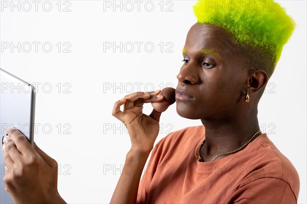 A gay black ethnic man putting on makeup