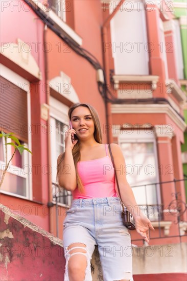 Young blonde caucasian woman in a street with houses with colorful facades smiling