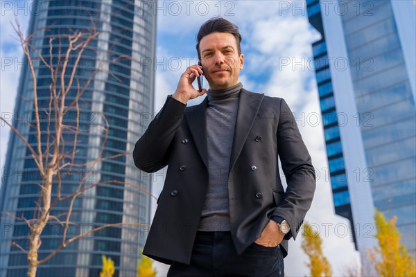 Corporate portrait of Caucasian businessman talking on the phone next to skyscraper office