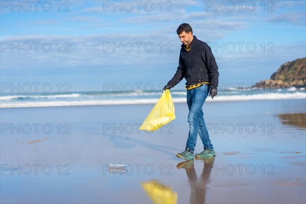 Man collecting garbage or plastic on the beach. Ecology concept