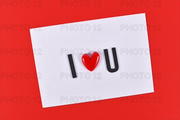 Valentine's day text 'I love you' spelled out with heart on white card on red background