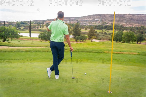 Young businessman playing golf and answering a work call with the phone
