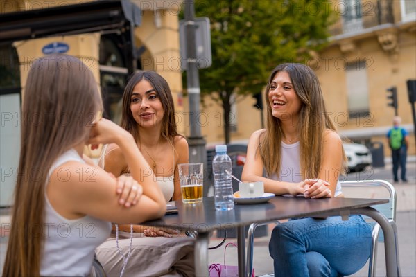 Portrait of young women friends having something one afternoon on a terrace of a cafeteria in autumn