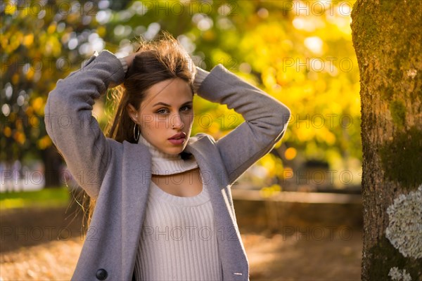 Pretty woman enjoying autumn in a park at sunset