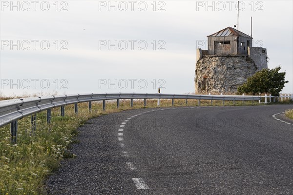 Coastal road and ruins of the historic lighthouse in the evening light on the cliff on Pakri Peninsula