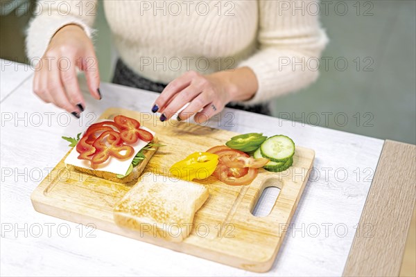 Unrecognizable person cooking a vegetable sandwich in the kitchen at home. Placing the red pepper