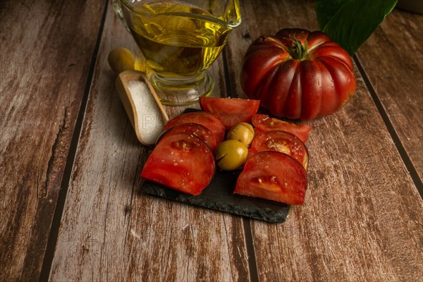 Chopped Moorish tomatoes with jar of olive oil and wooden spoon with salt