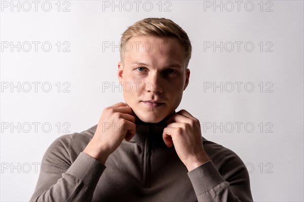 Portrait of an attractive blond german model with a brown sweater on a white background