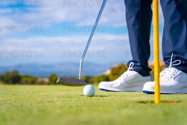 Putting the ball into the hole on the green with the putter. man playing golf