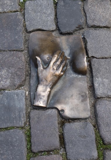 A miniature floor sculpture of a hand and a female titmouse on the Oudekerksplein