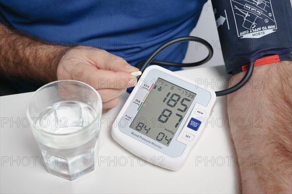 Older man with beard taking a pill after taking his blood pressure at home