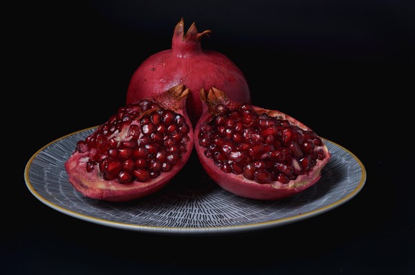 Fresh pomegranate opclose-up of fresh pomegranate opened on a yellow plate with black backgroundened on a plate with a black background