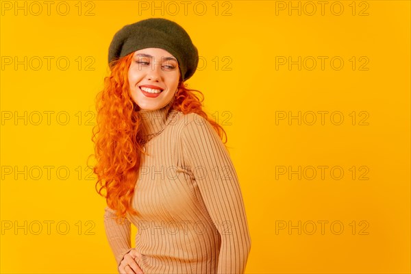 Red-haired woman in beret in studio on a yellow background