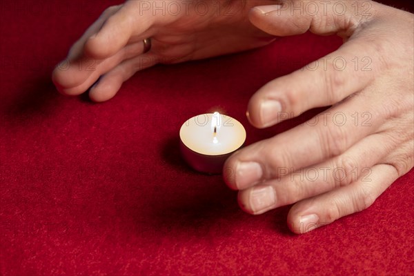 Hands warming themselves on burning tea light