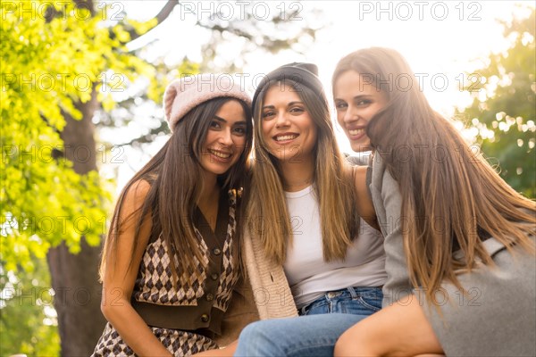 Women friends sitting in a park in autumn