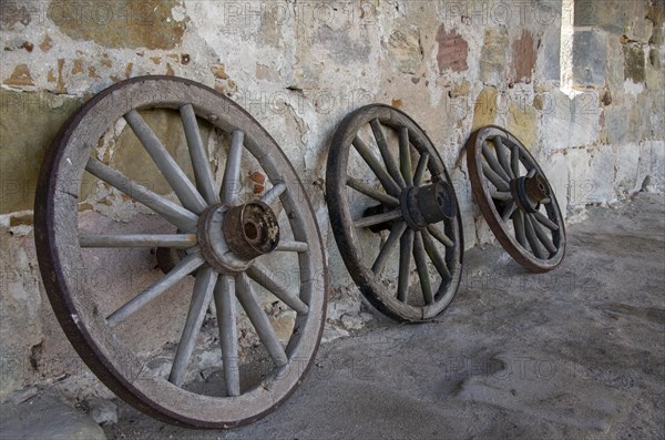 Historic old carriage wheels of carriages stand against an old sandstone wall