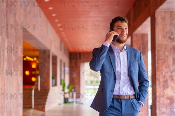 Corporate business or finance man telecommuting with the phone at the entrance of a hotel