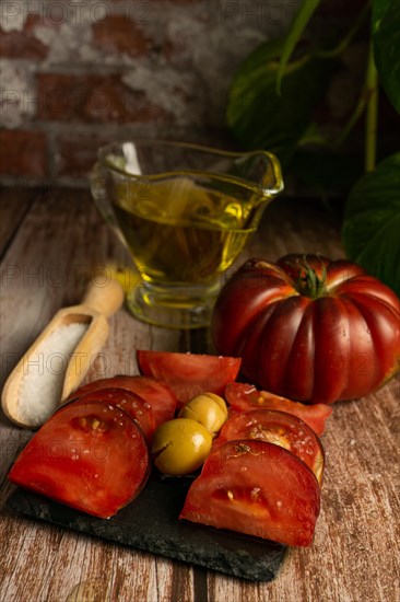 Chopped Moorish tomatoes with jar of olive oil and wooden spoon with salt