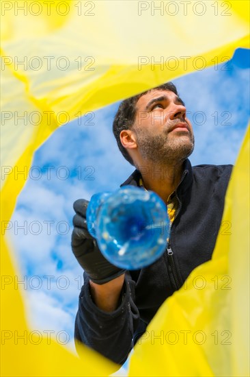 Portrait of man picking up trash on the beach. Ecology