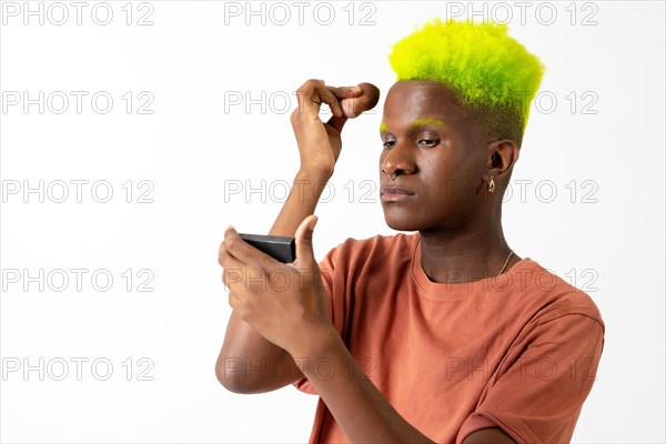 An androgynous black man posing putting on makeup