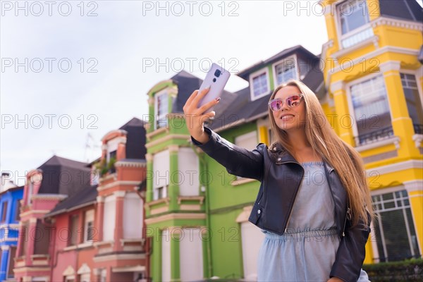 Young blonde with leather jacket taking a selfie with the mobile