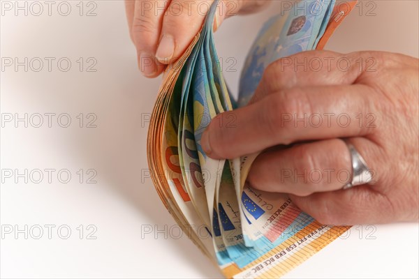 Woman counting euro banknotes on a white table with copy space