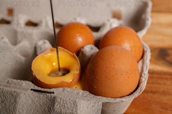 Woman beating an egg in its own shell with a small blender