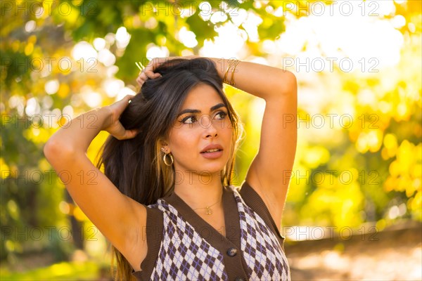 Portrait of a brunette model in autumn at sunset in a natural city park